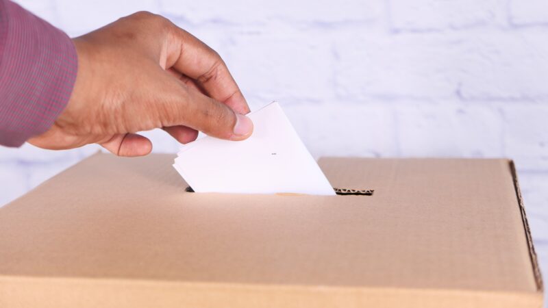 Mano poniendo un voto en urna