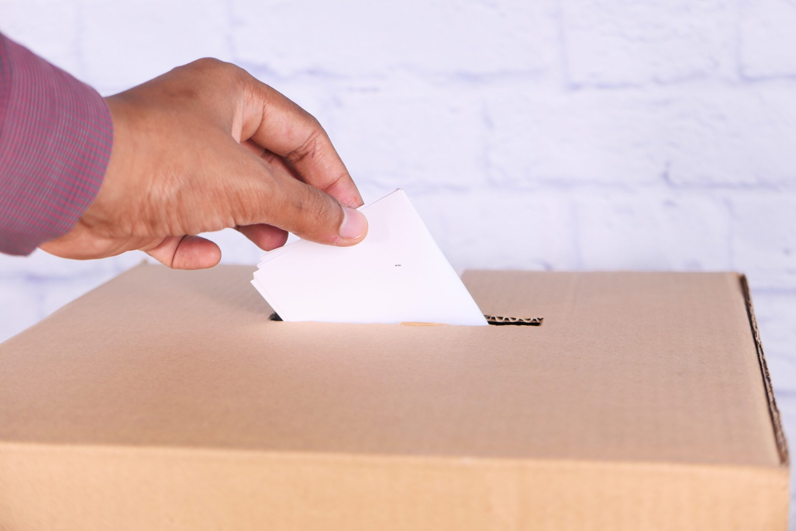 Mano poniendo un voto en urna
