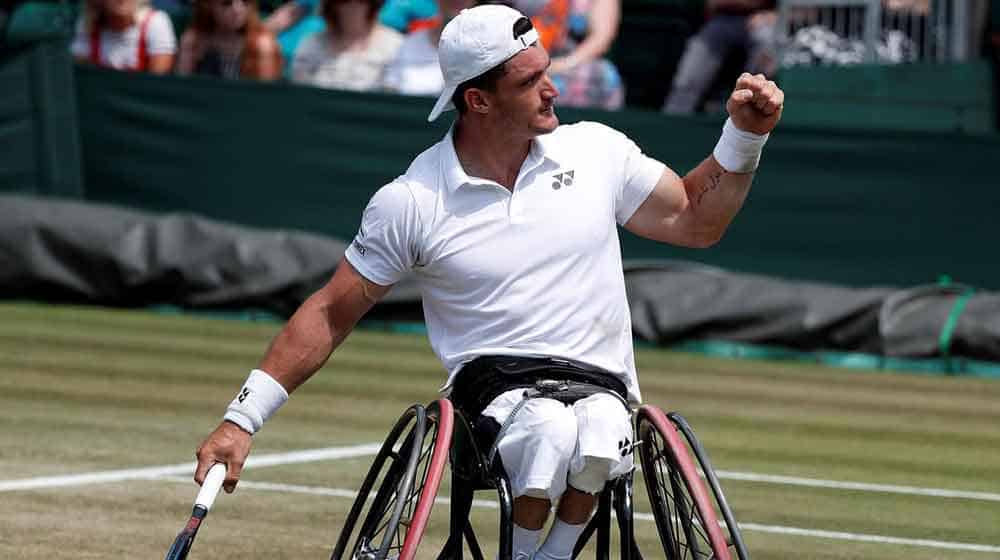 El tenista argentino Gustavo Fernández en su silla de ruedas celebrando un punto en un partido de tenis sobre una cancha de pasto.