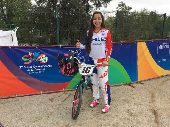 Una joven sonriendo junto a su bicicleta previo a una carrera de BMX