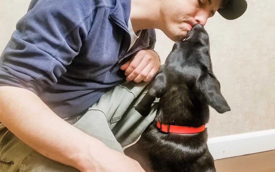 Un joven siendo lamido por su perro en la cara
