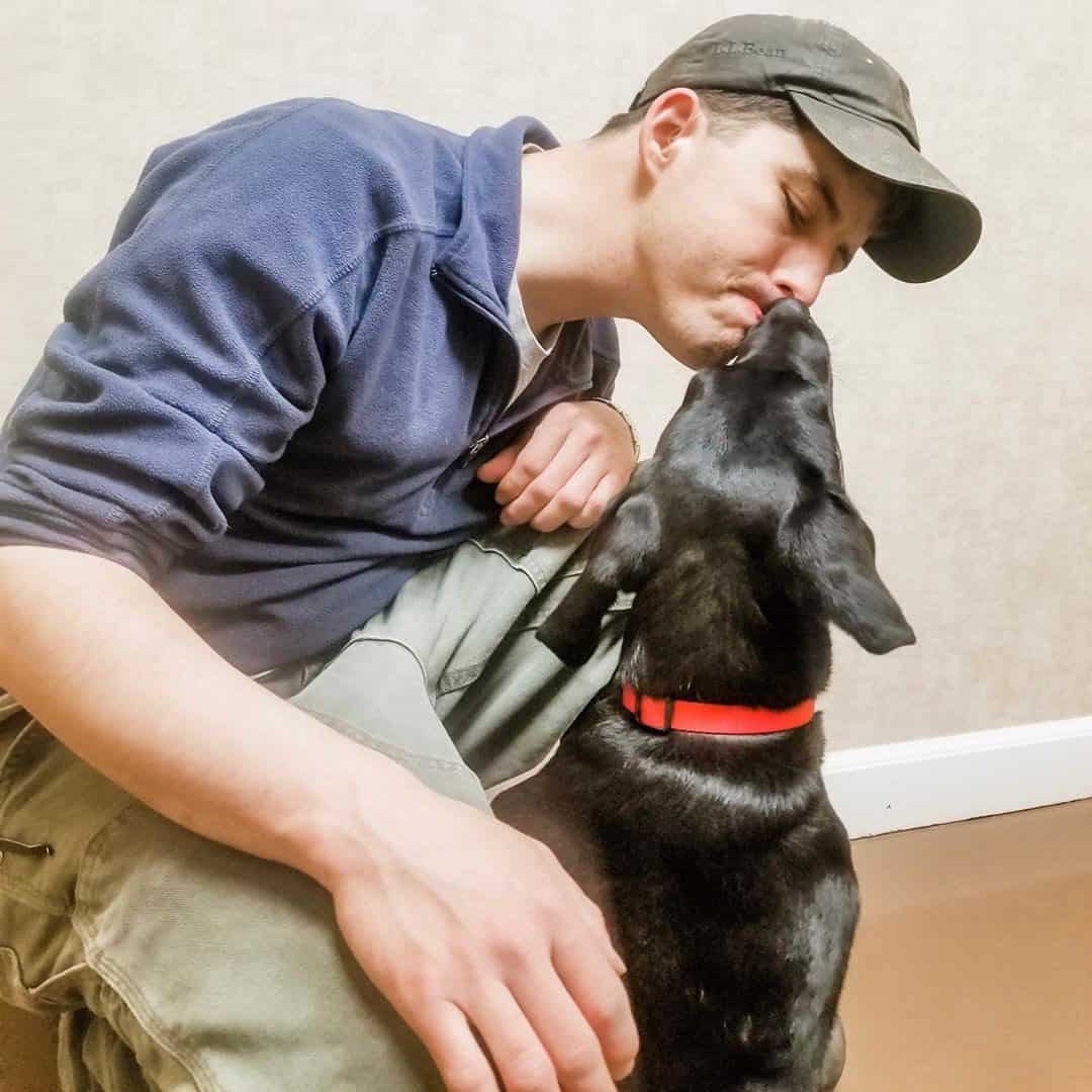 Un joven siendo lamido por su perro en la cara
