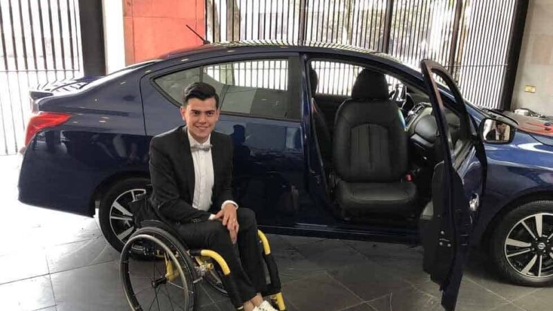 Un joven en silla de rudas posa para la foto al lado del nuevo auto adaptado