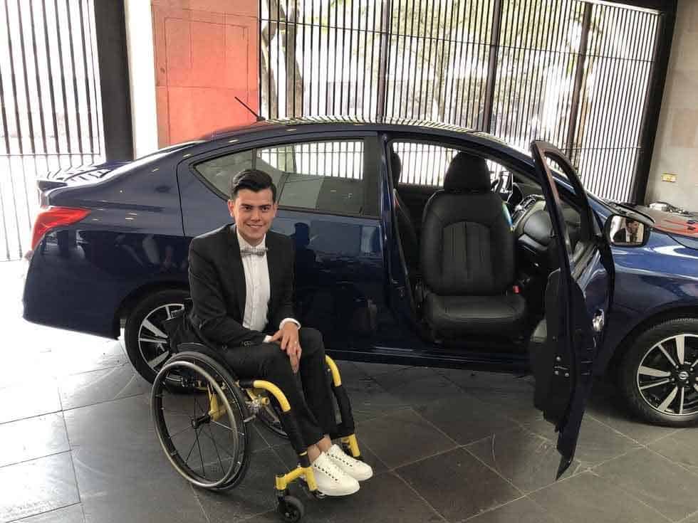 Un joven en silla de rudas posa para la foto al lado del nuevo auto adaptado
