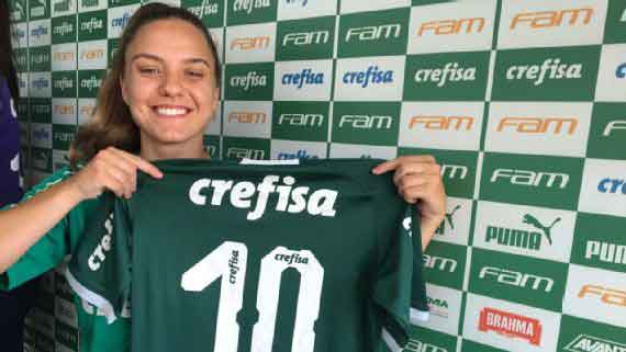 Una futbolista sorda sonriendo a la cámara y mostrando la camiseta que usará en su nuevo club