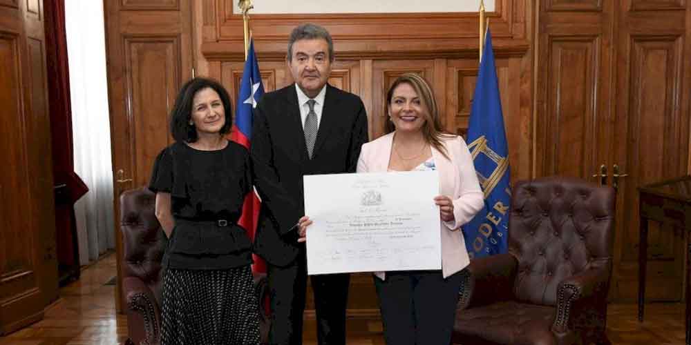Una mujer sorda aparece con su diploma del título profesional de abogada.