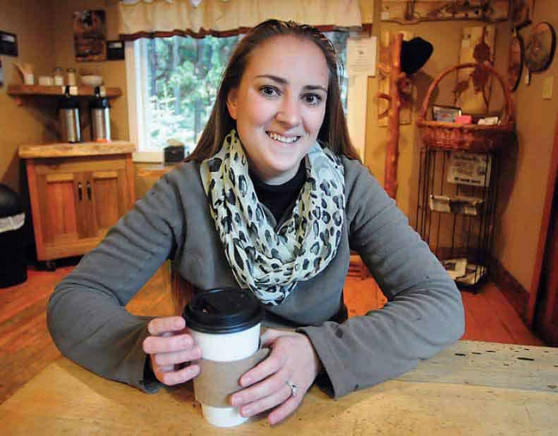 Una mujer sorda sentada en el living de su casa, tomando café y sonriendo a la cámara.