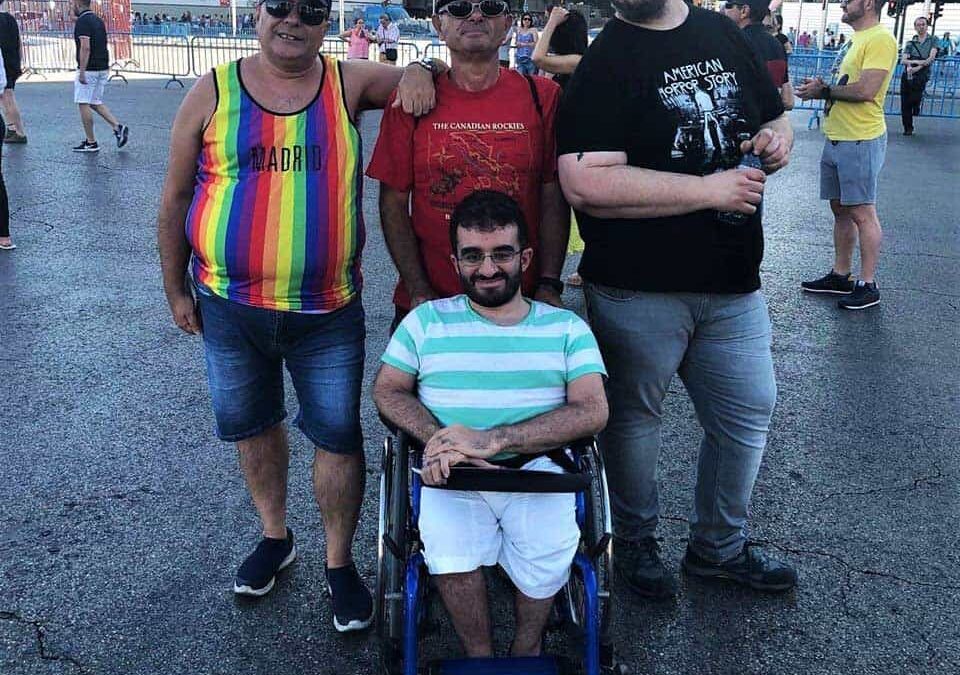 Foto donde aparecen 4 personas posando para la foto durante una marcha del Orgullo LGBTI en España. Están abrazados y uno de ellos está en silla de ruedas.