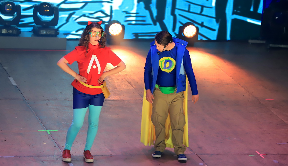 Dos personas sobre un escenario vestidos de súperheroes