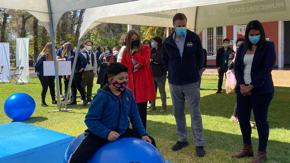 Niño saltando sobre una pelota azul y tres personas mirando