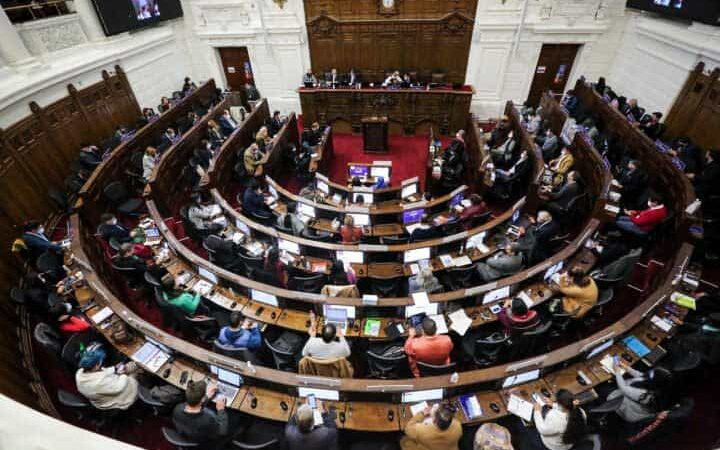 Foto del pleno de la convención constituyente donde aparecen varias personas votando en sus asientos.