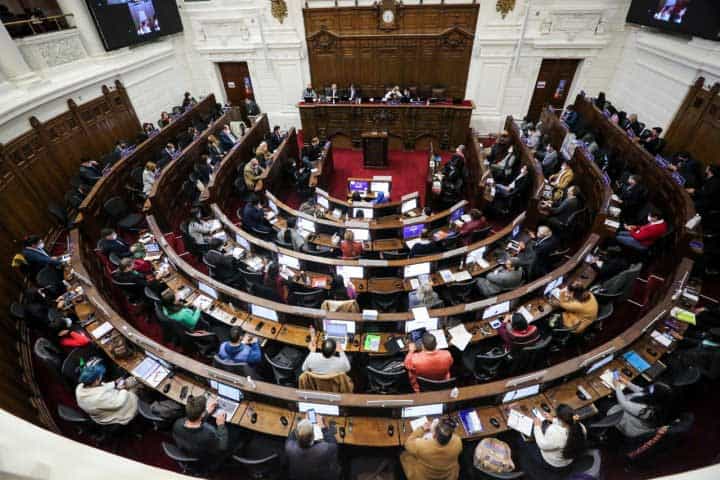 Foto del pleno de la convención constituyente donde aparecen varias personas votando en sus asientos.