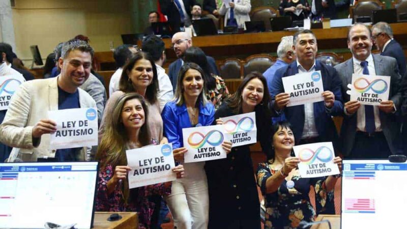 Foto dentro de la cámara de diputados donde aparece un grupo de diputados y diputadas sosteniendo carteles que dicen ley de autismo