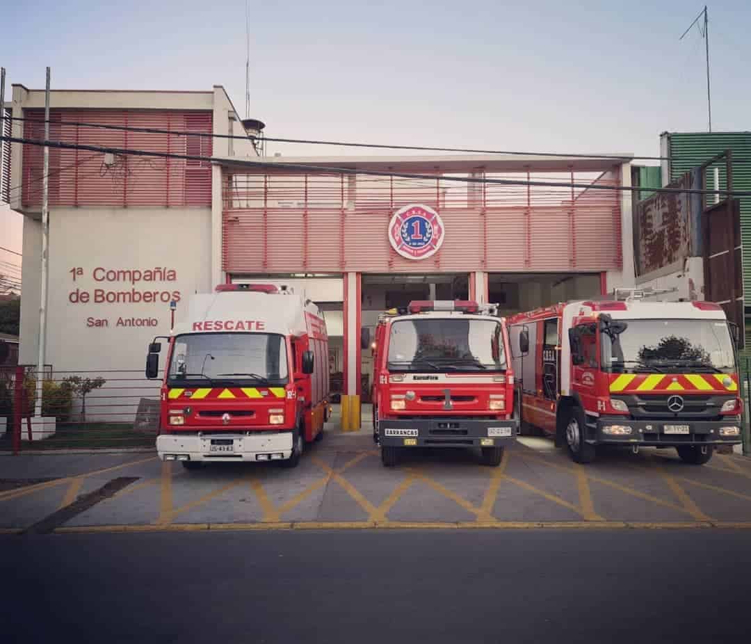 Foto de la 1era compañía de bomberos de san antonio donde hay 3 carros de bomberos grandes estacionados en la entrada.