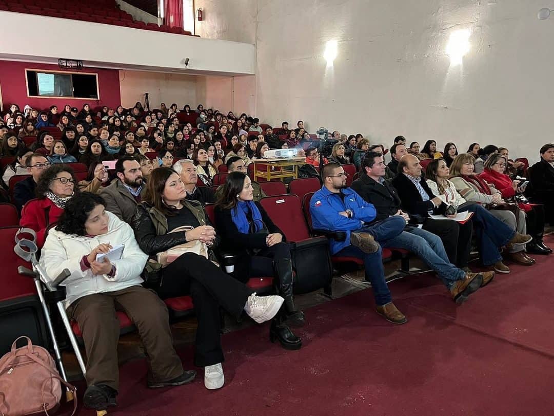Foto dentro de un auditorio de un instituto donde aparecen casi todos los asientos ocupados con personas que están atentas a la charla.