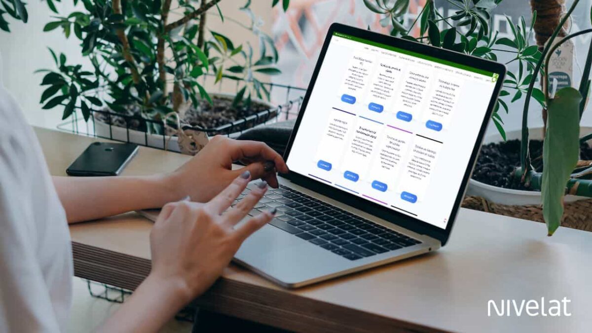 Foto donde aparecen las manos de una persona sentada en un escritorio y con un computador en frente. En el computador está la web de fundacionwazu.cl y sale una lista de diferentes cursos.