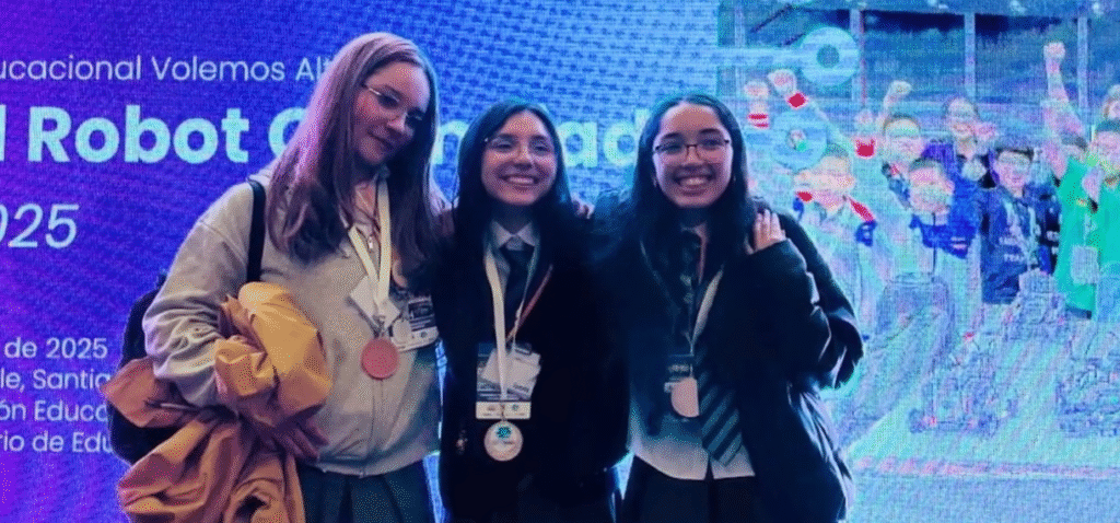 Tres jóvenes sonriendo a la cámara con medallas colgando de sus cuellos