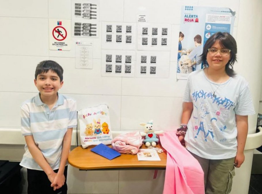 Una niña y un niño junto a una mesa donde hay un peluche de contención emocional