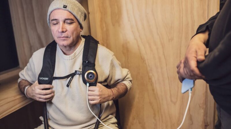Hombre sentado con ojos cerrados sintiendo música con chaleco vibratorio