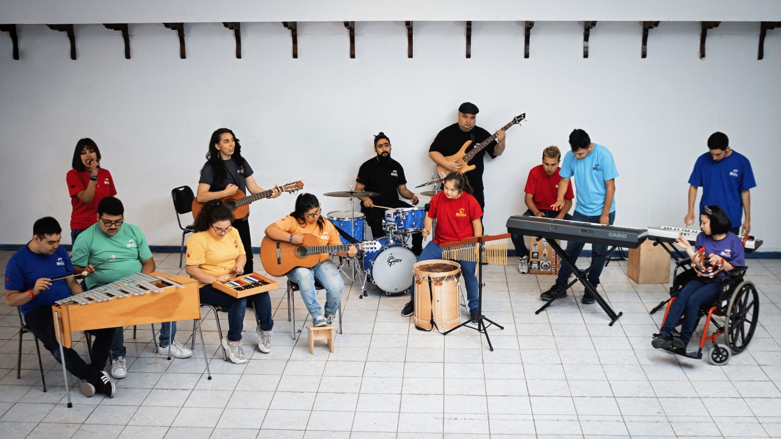 Grupo de personas, sentadas y de pies tocando instrumentos