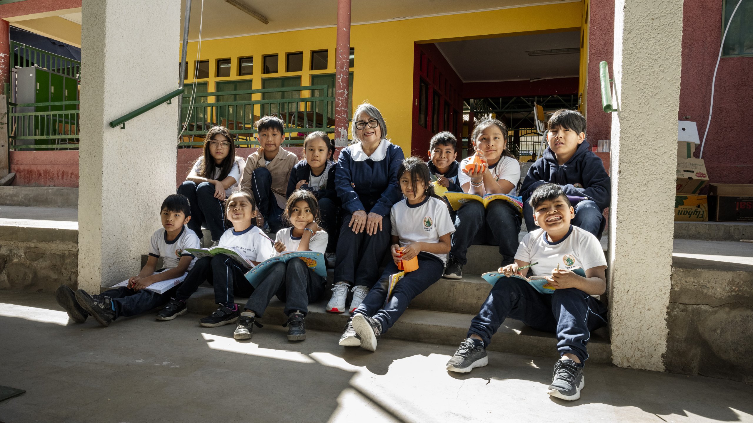 Profesora rodeada de sus estudiantes sentados en una escalera