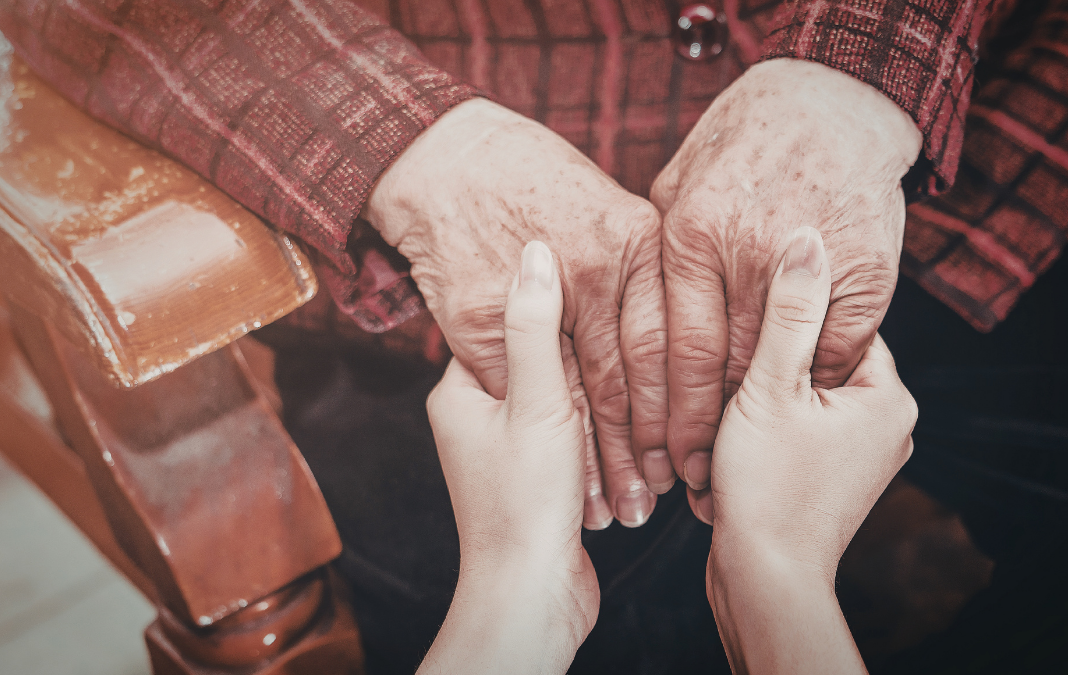 Manos de adulto mayor de la mano de cuidadora