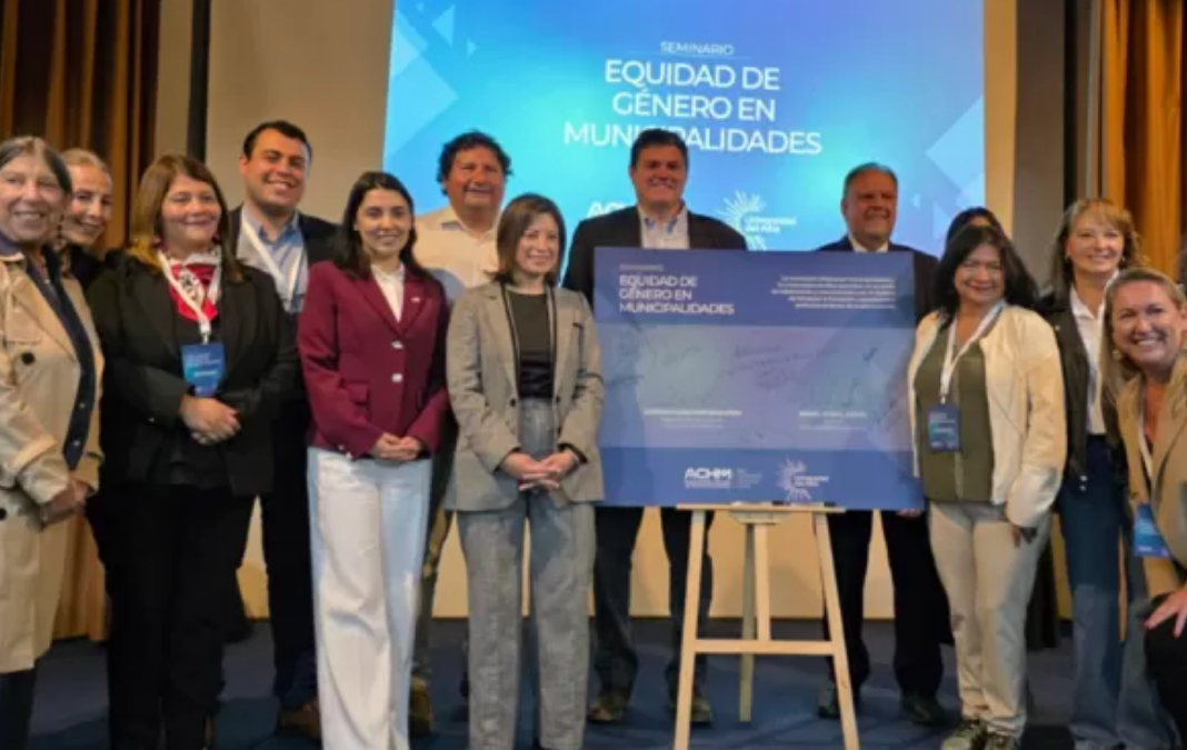 Fotografía de diversas personas posando a una fotografía junto a un cartel azul