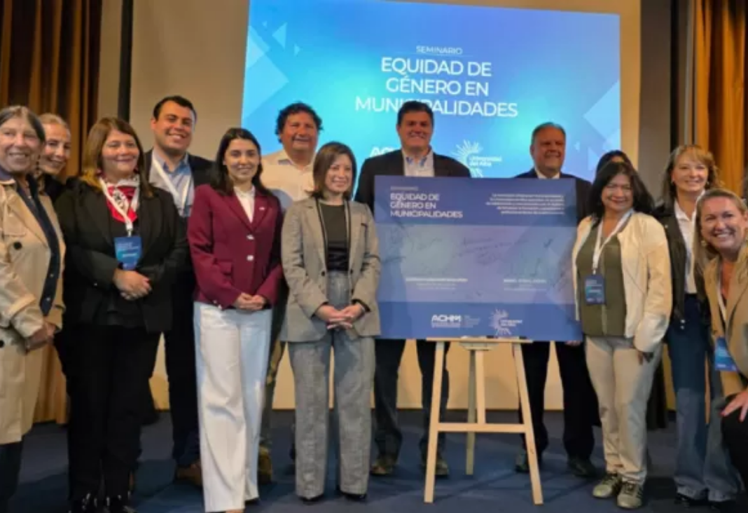 Fotografía de diversas personas posando a una fotografía junto a un cartel azul