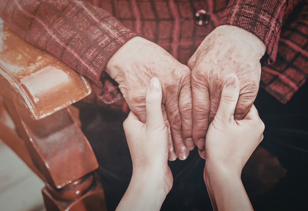 Manos de adulto mayor de la mano de cuidadora