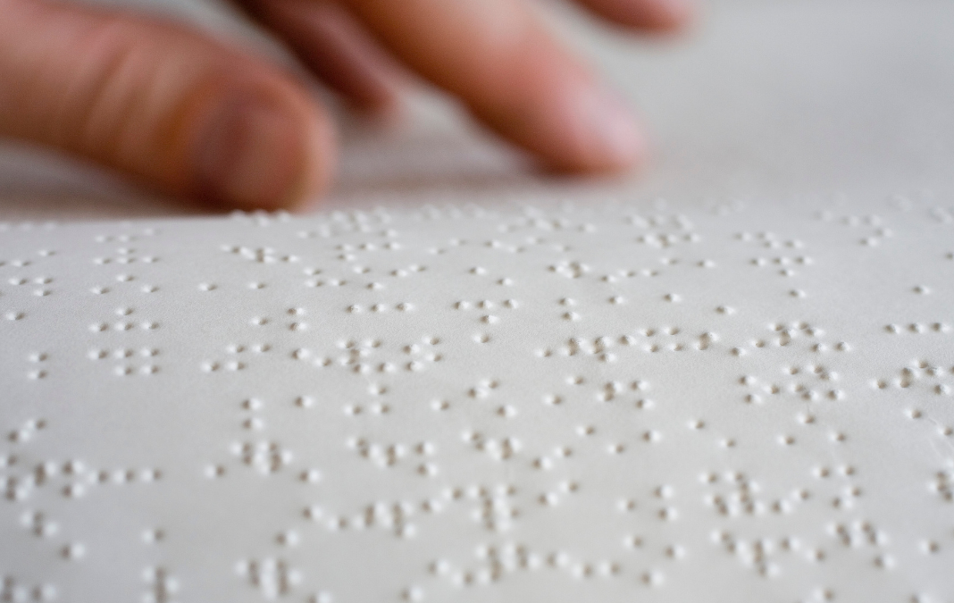 Una mano sobre una hoja escrita con Braille