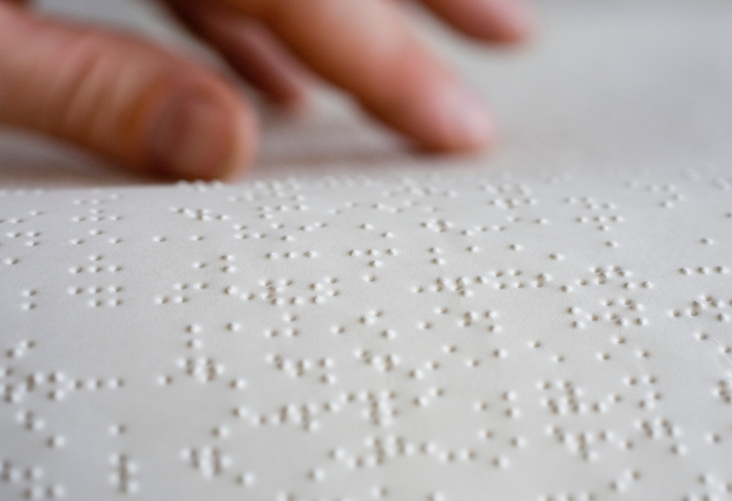 Una mano sobre una hoja escrita con Braille