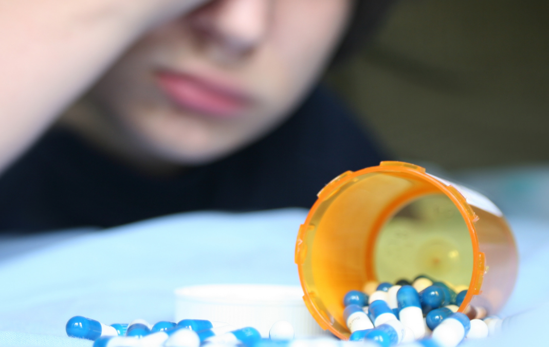 Fotografía de un envase de medicamentos y detrás un niño
