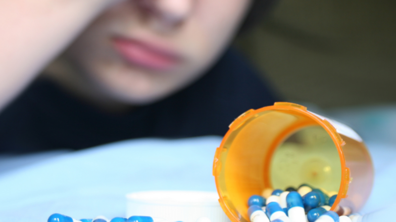 Fotografía de un envase de medicamentos y detrás un niño