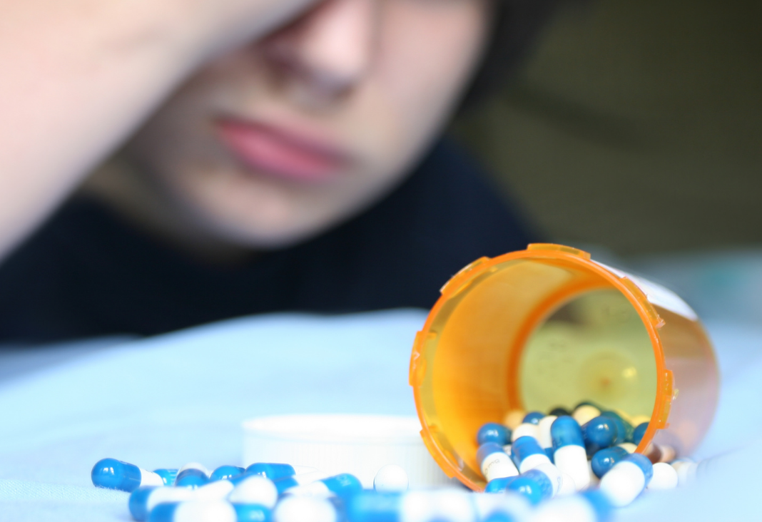 Fotografía de un envase de medicamentos y detrás un niño