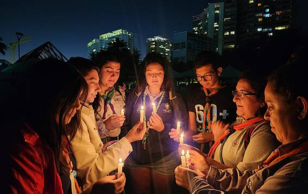 seis personas en un semi círculo con velas en sus manos