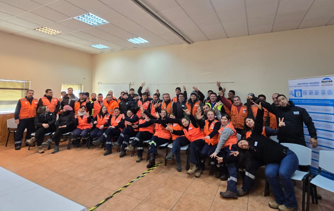 Trabajadores con chalecos naranja saludando a la cámara