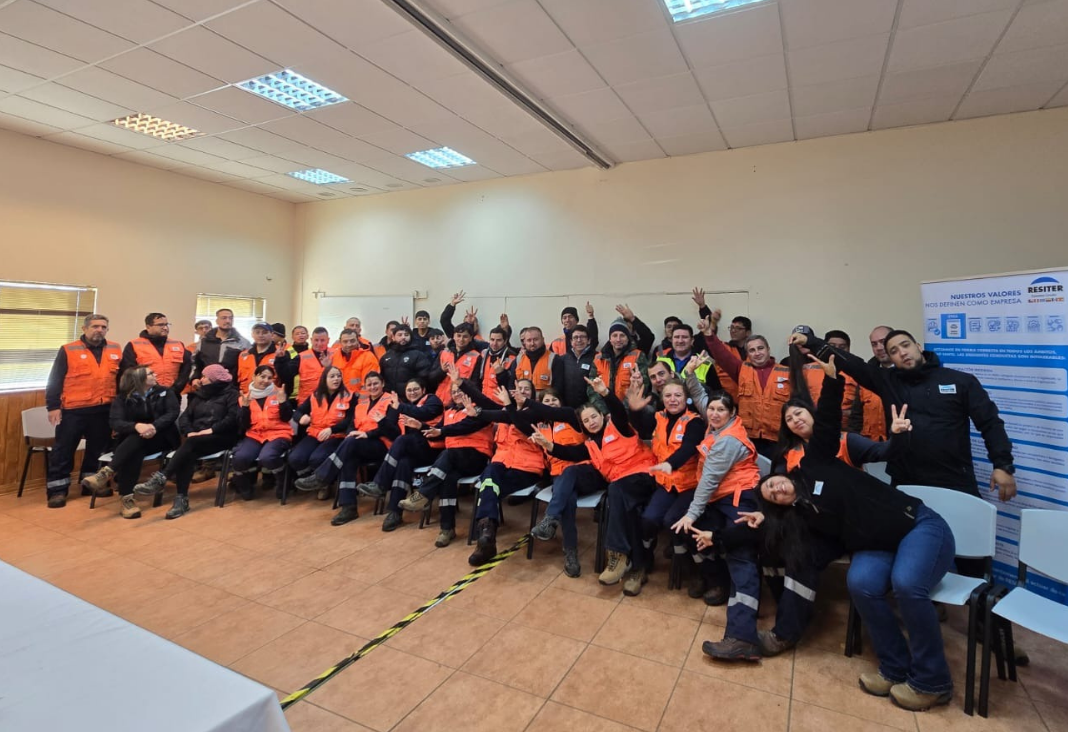 Trabajadores con chalecos naranja saludando a la cámara