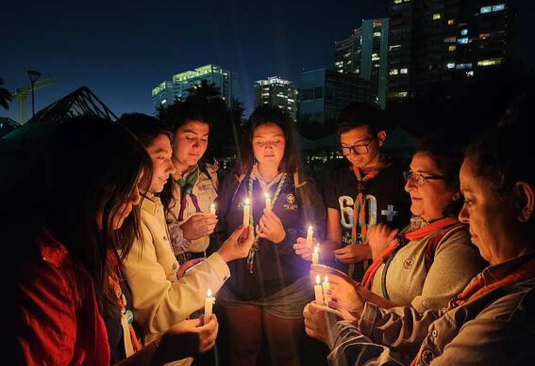 seis personas en un semi círculo con velas en sus manos