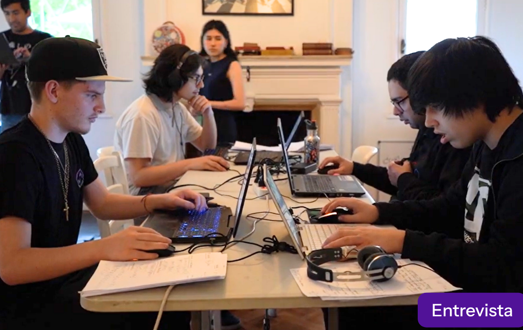 Cuatro jóvenes sentados frente a computadores en torno a una mesa