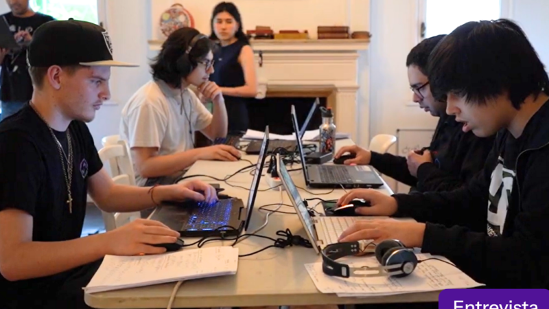 Cuatro jóvenes sentados frente a computadores en torno a una mesa