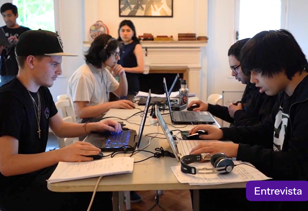 Cuatro jóvenes sentados frente a computadores en torno a una mesa