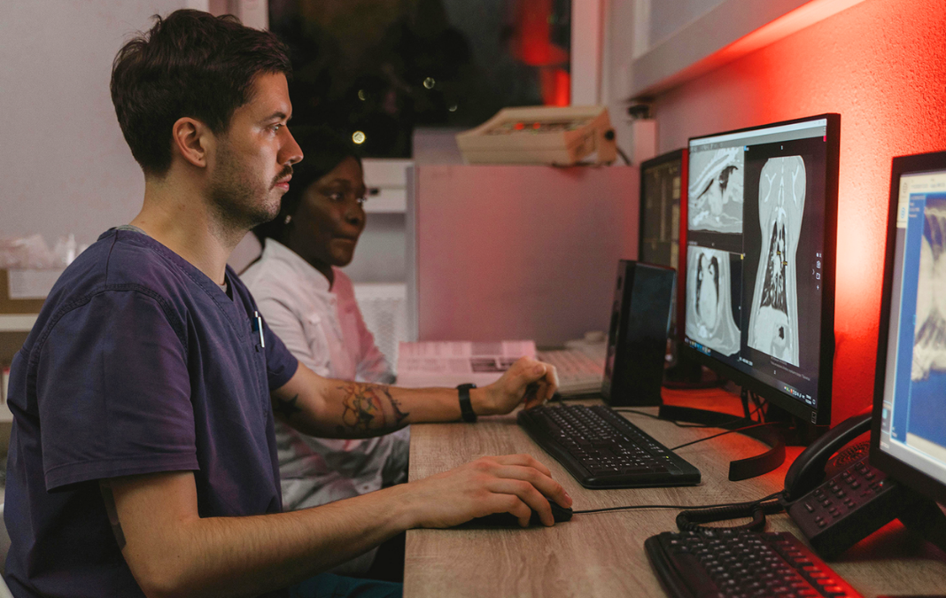 Foto de médico sentado frente a un computador revisando imagen de tórax