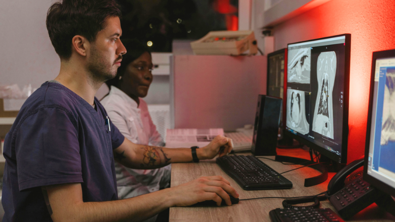 Foto de médico sentado frente a un computador revisando imagen de tórax