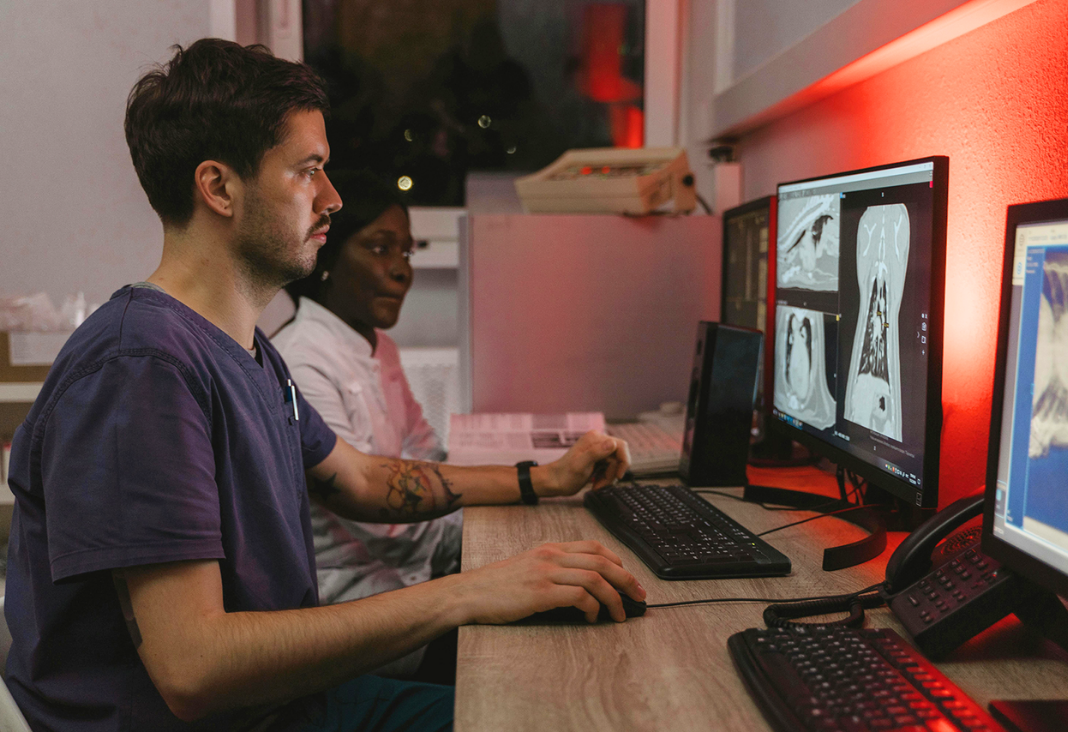 Foto de médico sentado frente a un computador revisando imagen de tórax