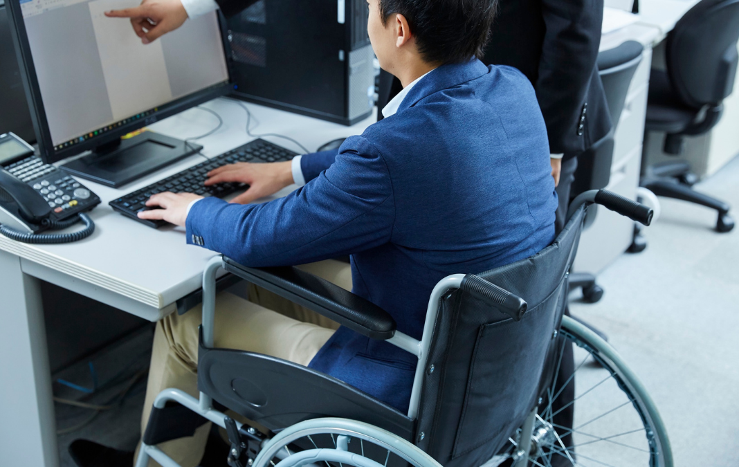 persona en silla de ruedas frente a un computador trabajando
