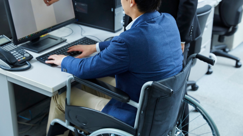 persona en silla de ruedas frente a un computador trabajando