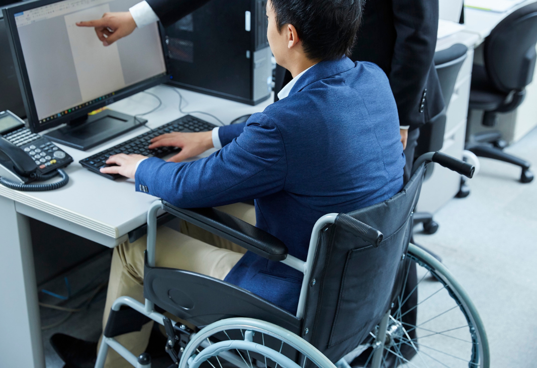 persona en silla de ruedas frente a un computador trabajando