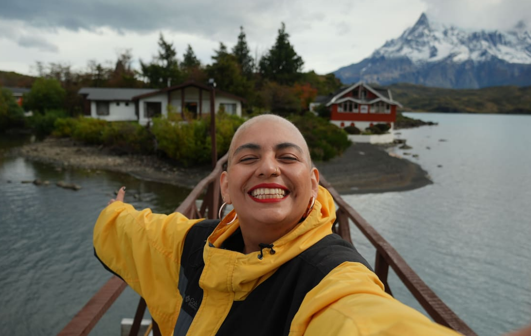 Mujer sonriendo y mostrando el paisaje de Magallanes detrás de ella