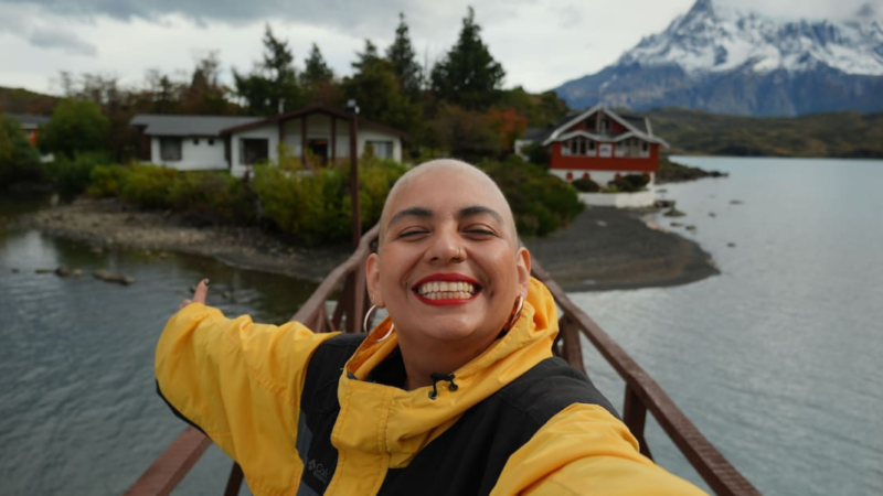 Mujer sonriendo y mostrando el paisaje de Magallanes detrás de ella