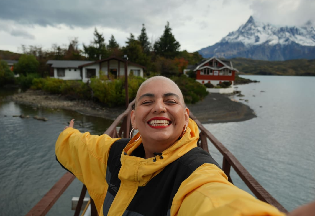 Mujer sonriendo y mostrando el paisaje de Magallanes detrás de ella